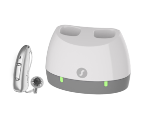 silver hearing aid next to a charging case