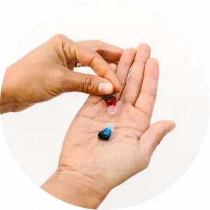 small blue and red hearing aids in the palm of a hand 